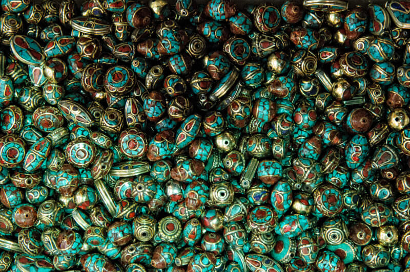 Close-up of beaded pendants inlaid with turquoise and coral fragments at a Grand Bazaar jewelry stall