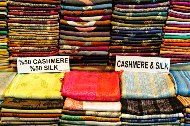 Colorful cashmere and silk scarves stacked in rows with cashmere-silk signage at a Grand Bazaar shop