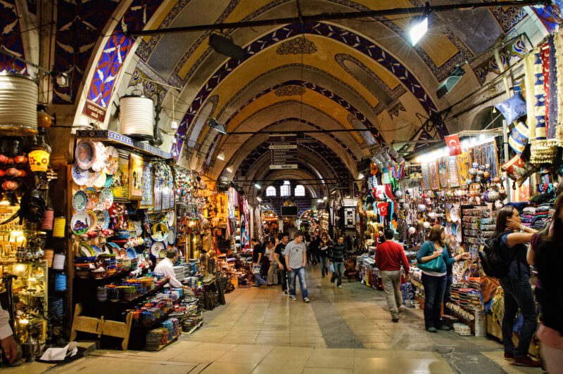 Wide central street of the Grand Bazaar lined with shops beneath an Ottoman-style painted arched ceiling