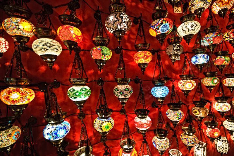 Dense grid of mosaic glass lamps in red, blue, amber and green hanging inside a Grand Bazaar shop
