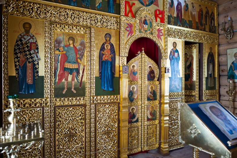 Painted icons arranged across gilded iconostasis glowing in the interior of Trinity Church, King George Island