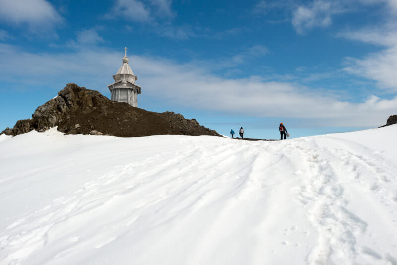 Visitors ascending steep snowy slope toward Trinity Church above Bellingshausen Station, King George Island