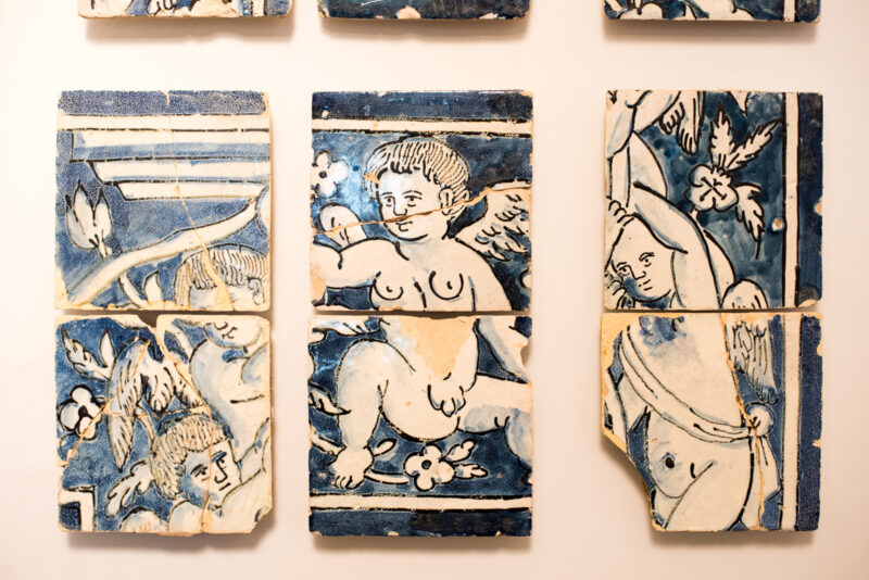 Fragmented blue-and-white azulejo tiles with cherub motifs displayed at the Castelo de São Jorge museum