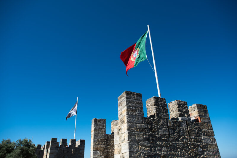 Portuguese and Lisbon flags fly above the crenellated stone battlements of Castelo de São Jorge