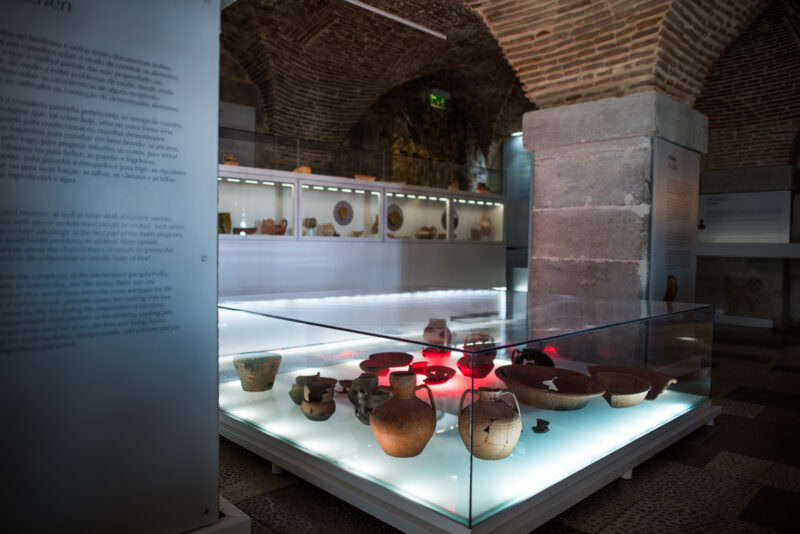 Ancient pottery vessels lit in a glass display case at the Castelo de São Jorge archaeological museum