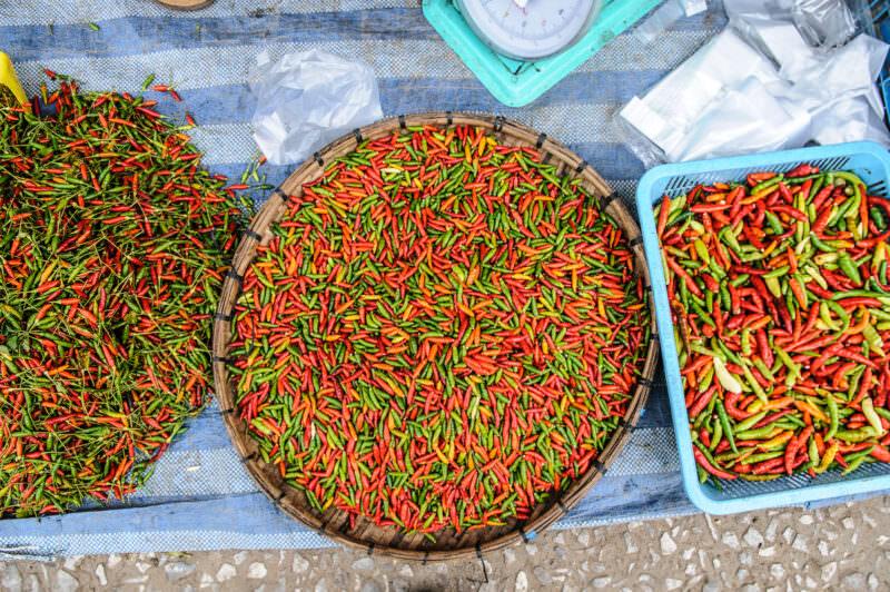 Mak phet kii nuu chilies in a woven tray, tiny green and red pods heaped at a Luang Prabang market