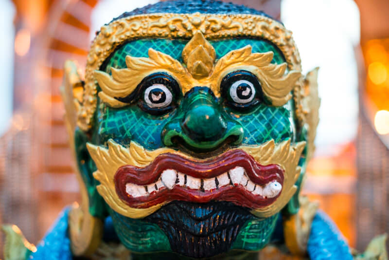 Green-faced Sandamukhi ogress statue at Sutaungpyei Pagoda, gold crown and wide staring eyes in close-up, fanged mouth open