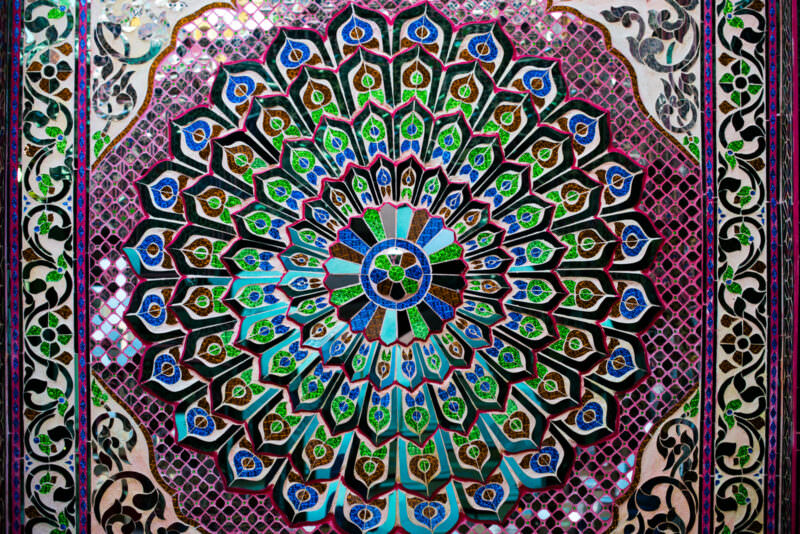 Mirrored-glass mosaic wall at Sutaungpyei Pagoda showing radiating floral mandala in colored and mirror-cut glass tiles