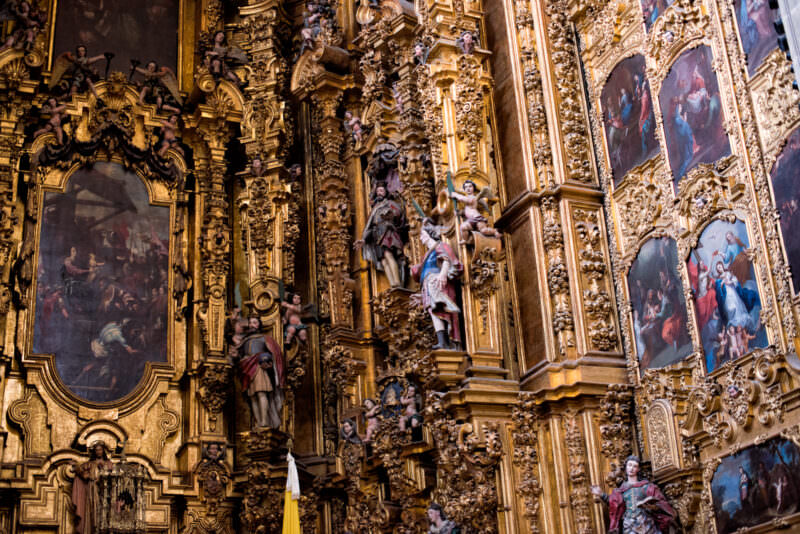 Gold-leafed estípite pilasters and polychrome sculptures crowding the lateral face of the Altar de los Reyes