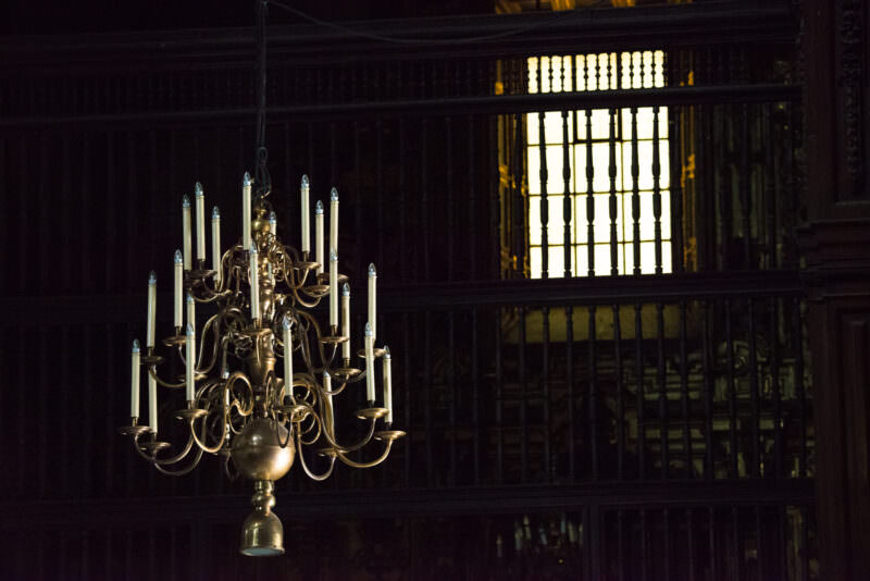 Brass candelabrum hanging before the cathedral's dark choir enclosure and iron grille
