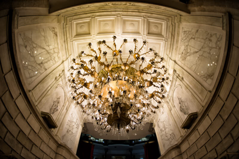 Multi-tiered crystal chandelier centered beneath coffered dome at Gran Hotel Ciudad de Mexico entrance, framed by veined marble