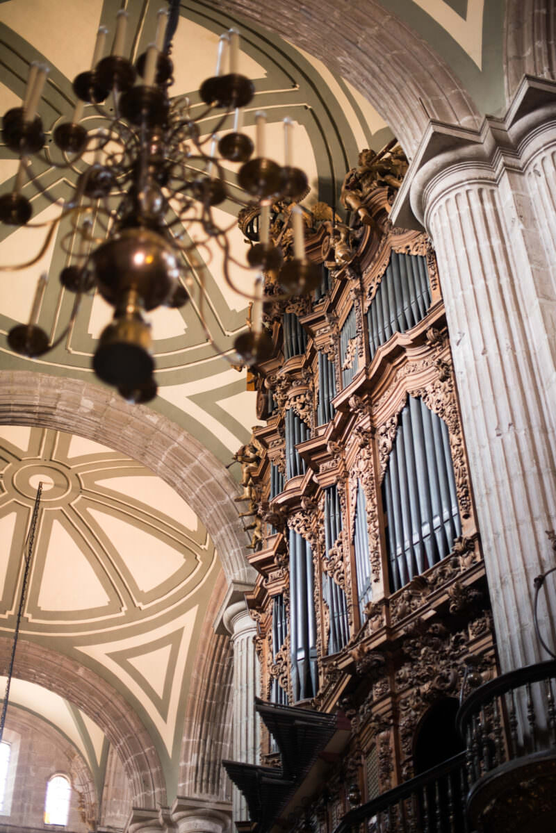 Monumental pipe organ seen from below against ribbed vaulting and a fluted cantera column