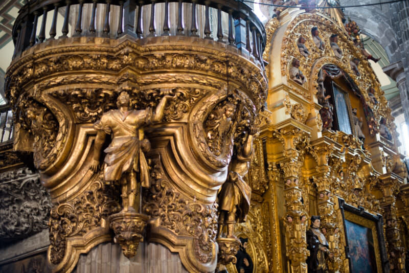 Gilded Baroque pulpit detail in Catedral Metropolitana, carved figures beneath a retable thick with gold ornament