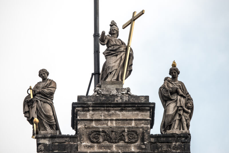 Three Neoclassical stone virtues—Faith, Hope, and Charity—crowning the cathedral's main facade clock section