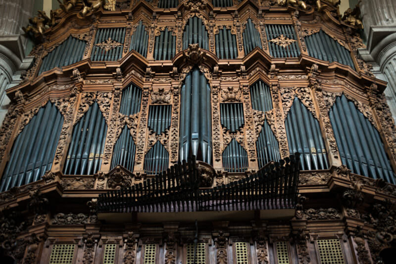 Baroque pipe organ case, pewter-grey metal pipes within cascading carved acanthus scrollwork and cherubs