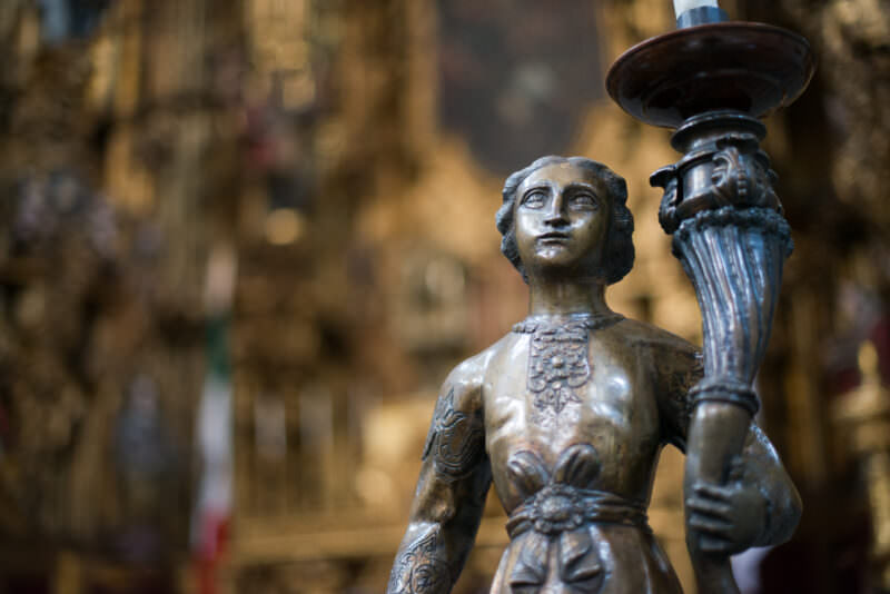 Bronze figural candle holder with embossed drapery before the gilded Altar de los Reyes