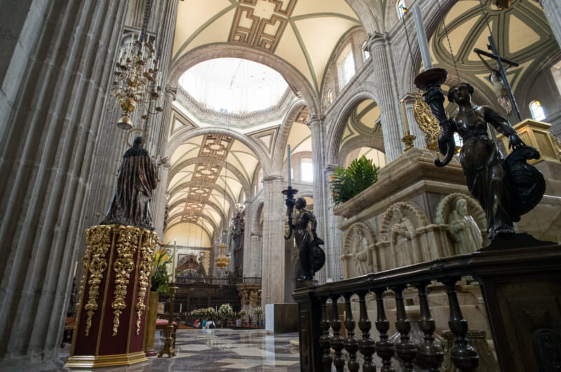 Bronze candle holders and marble altar furnishing beneath Manuel Tolsá's octagonal dome flooding light