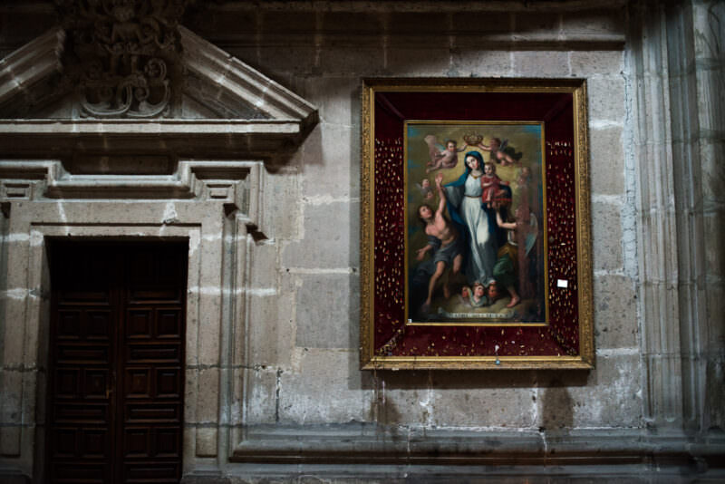 Colonial devotional painting of the Virgin hanging on a white limestone wall beside a classical doorway