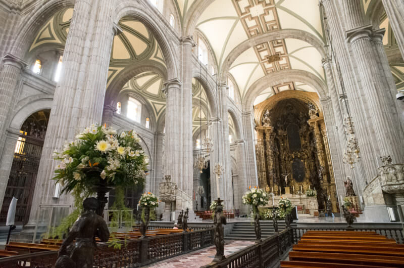 Catedral Metropolitana nave looking toward the gilded Altar de los Reyes, white flowers on the choir rail