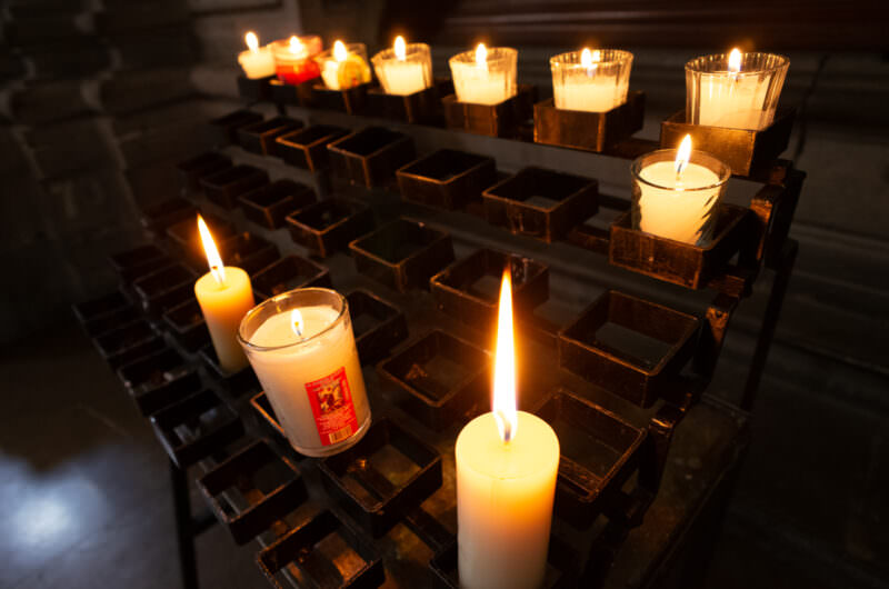 Votive candles burning in glass holders on an iron rack inside the cathedral
