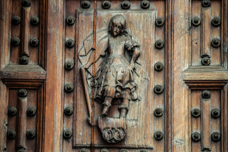 Weathered wood-relief panel of a winged figure carved on a cathedral door