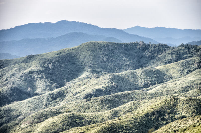 Steep forested mountain ridges fading into layers of blue haze in the northern highlands of Laos