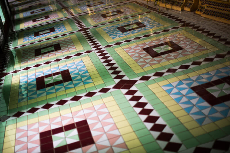 Polychromatic geometric floor tiles in green, blue, red, yellow and white with light from arched opening at U Min Thonze Pagoda