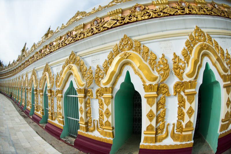 U Min Thonze Pagoda's convex outer wall with thirty gilded-stucco arches sweeping along Sagaing Hill under cloudy sky