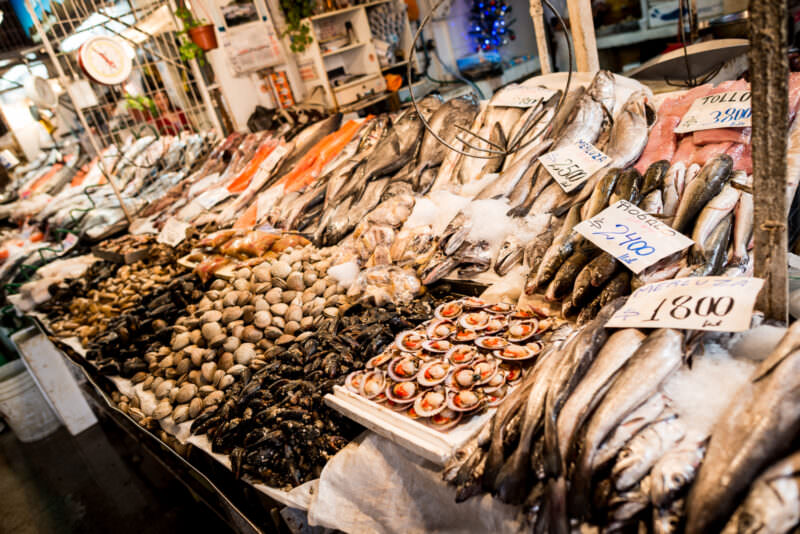 Extensive seafood display at Mercado Central with whole fish, mussels, clams, and scallops on ice with handwritten price tags