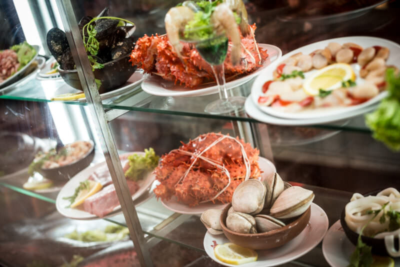 Chilean king crab with orange-red shell displayed in glass case alongside other prepared seafood dishes at Mercado Central restaurant