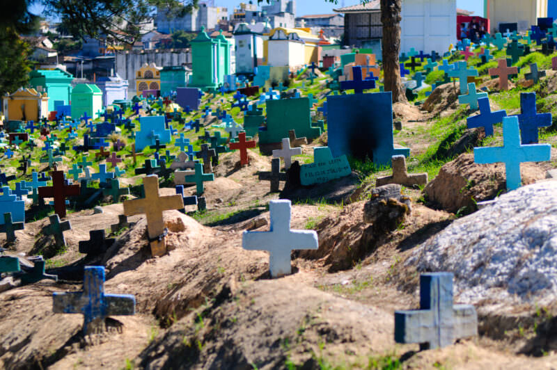 Hillside cemetery in Chichicastenango with bright blue, green, and multicolored painted crosses and mausoleums