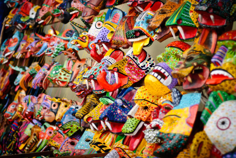 Dense display of brightly painted wooden animal and mythical creature masks hanging at Chichicastenango market