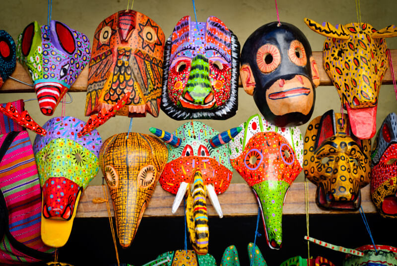 Rows of hand-painted wooden animal masks in vivid colors, displayed hanging on market stall in Chichicastenango