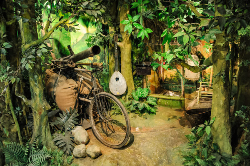 Reinforced supply bicycle loaded with a weapon tube and cargo sacks in a jungle diorama