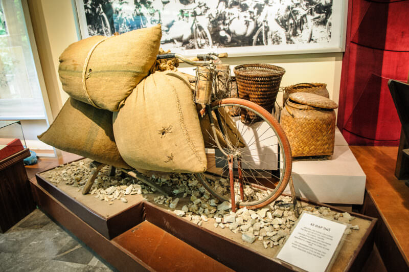 A reinforced pack bicycle loaded with burlap sacks and woven baskets, a Ho Chi Minh Trail supply exhibit