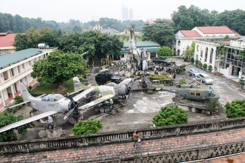 Aerial view of the Vietnam Military History Museum courtyard with captured aircraft, tanks, and a wreckage-built tower