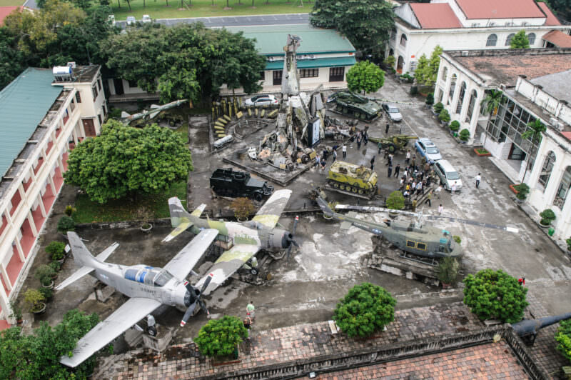 Aerial view of the museum courtyard with aircraft wreckage sculpture, tanks, and a Huey helicopter on display
