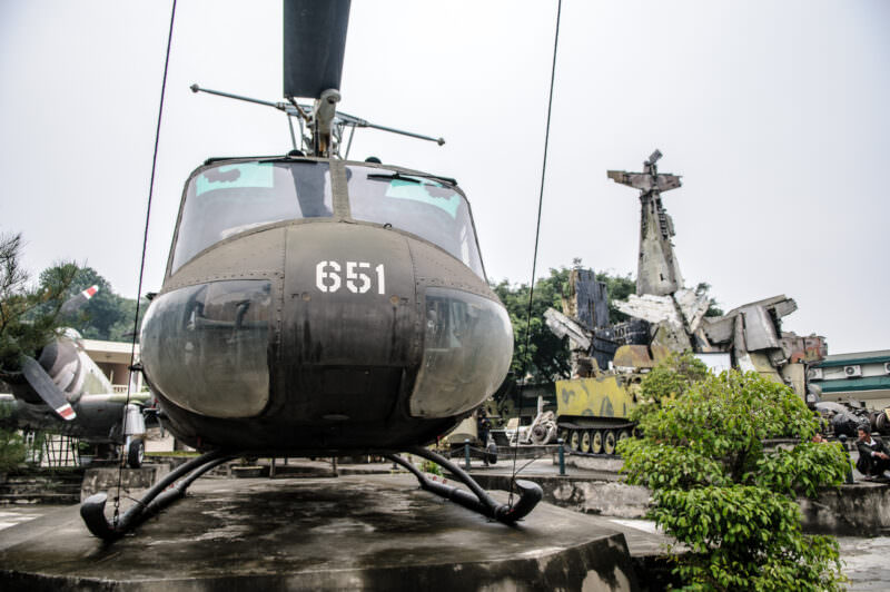 Captured Bell UH-1 Iroquois helicopter facing the camera in the Vietnam Military History Museum's outdoor yard