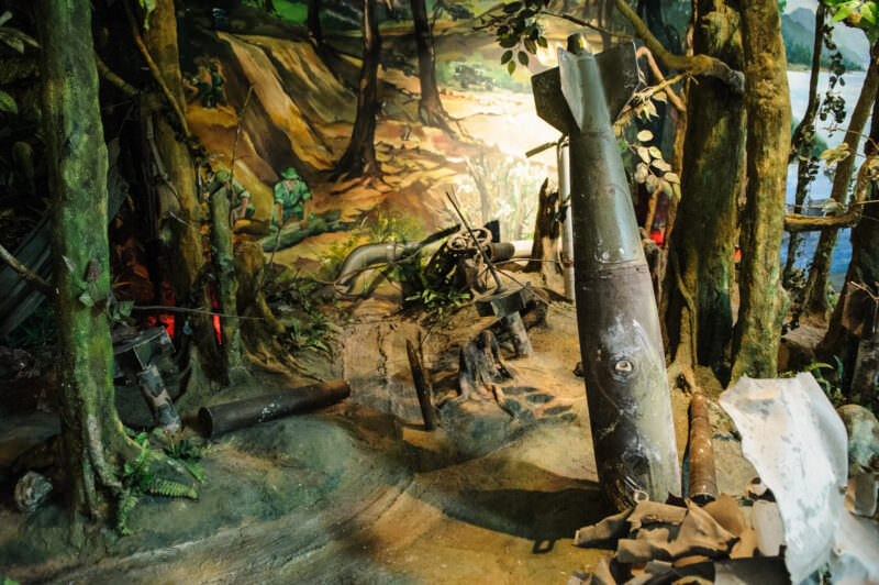 Jungle diorama with an unexploded bomb and scattered ordnance against a painted forest backdrop