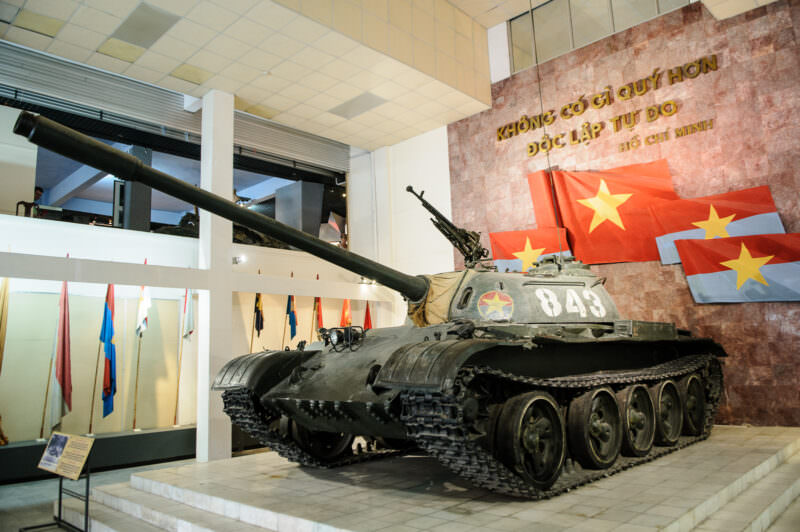 Soviet-built T-54B tank numbered 843 on display beneath a red-starred flag wall inside the museum
