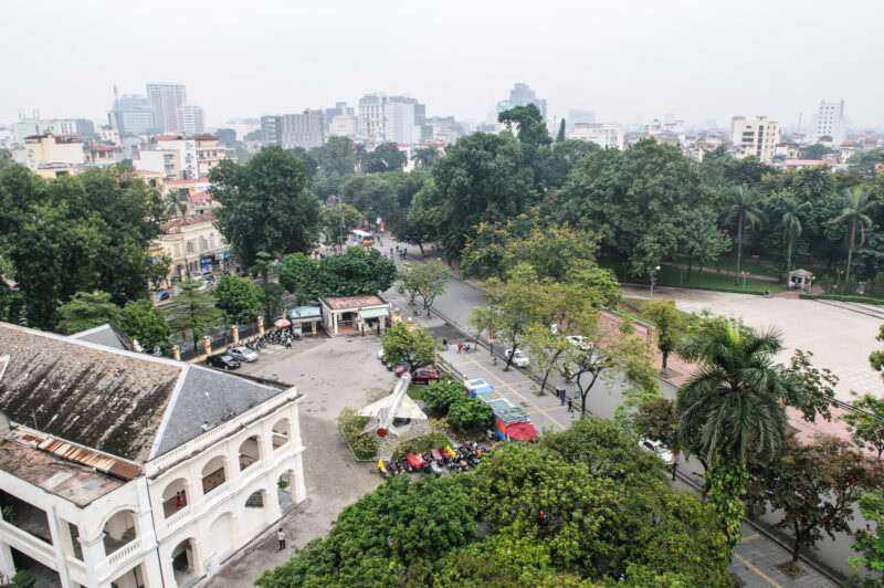 Elevated view from the Flag Tower over the museum courtyard, a MiG jet, and Hanoi's Ba Đình skyline