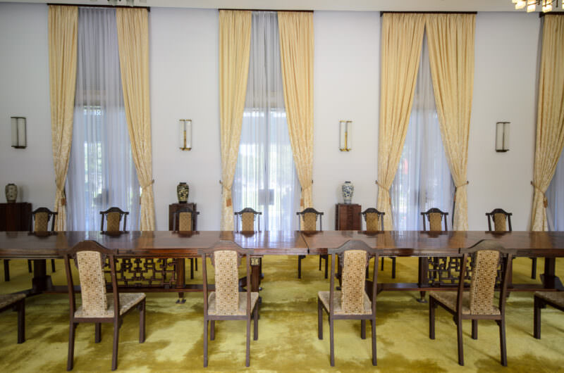 Long fretwork-carved wooden table lined with chairs in Reunification Palace's Banquet Chamber