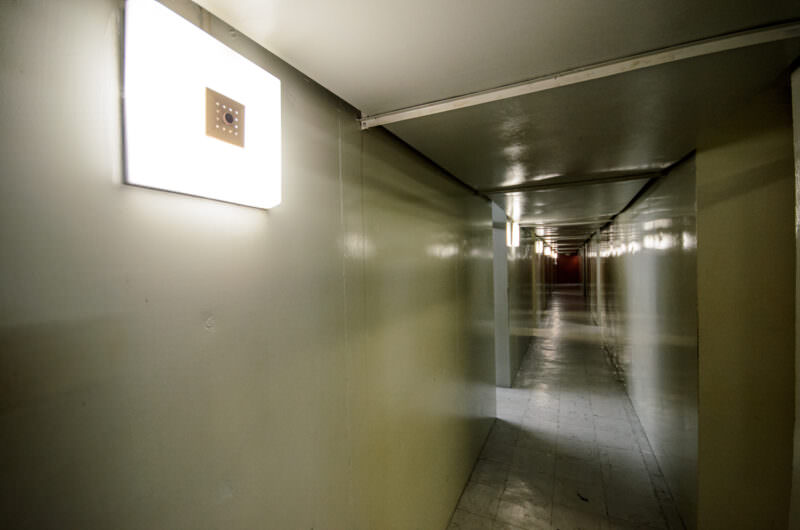 Dimly lit corridor with square wall sconces inside Reunification Palace's basement command bunker