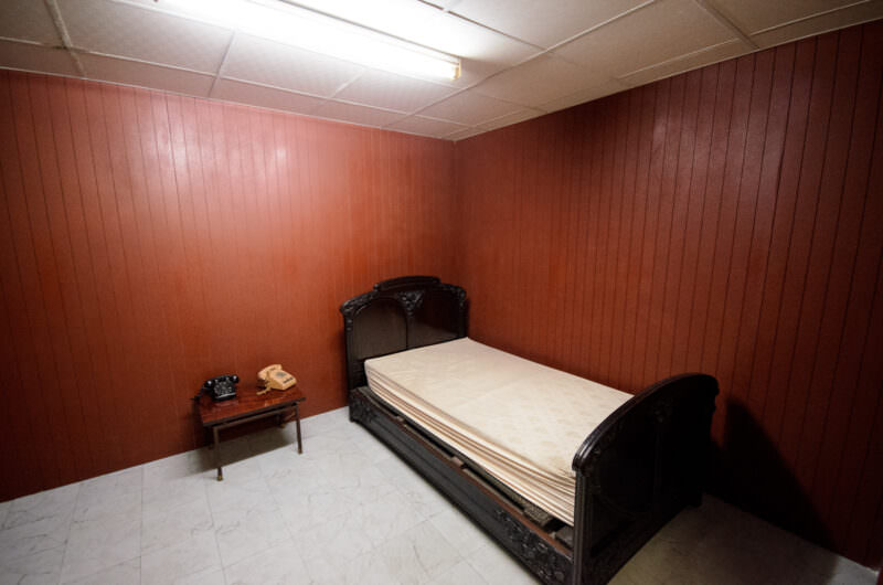 Carved wooden bed and bedside rotary phones in the windowless presidential bunker bedroom at Reunification Palace