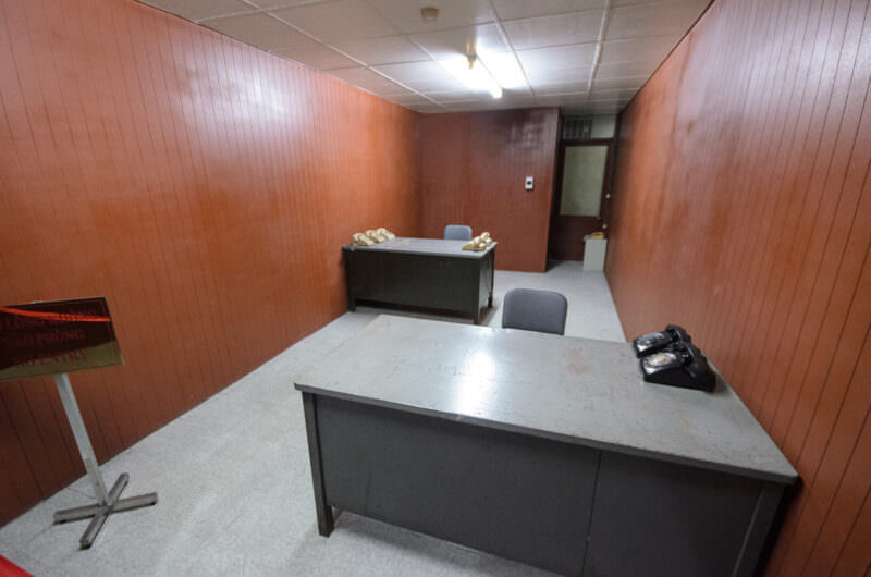 Two metal desks with rotary phones in a wood-paneled military aide's office in Reunification Palace's bunker