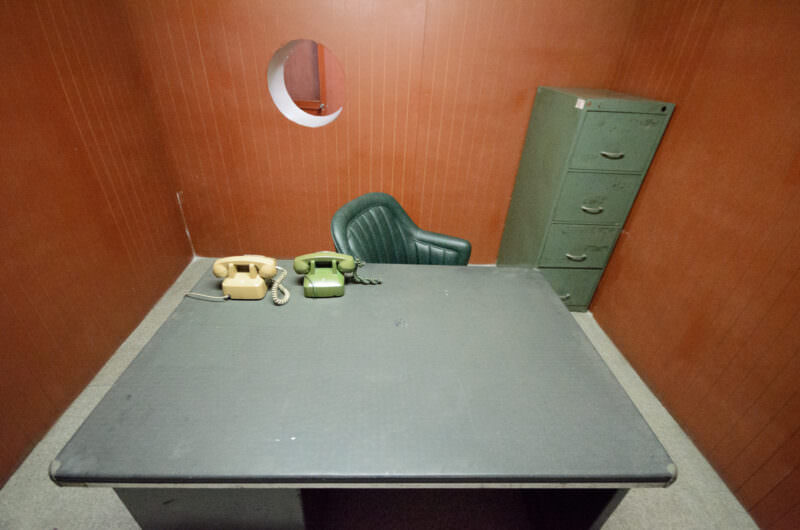 Rotary phones and filing cabinet in a military aide's office with a round window in Reunification Palace's bunker