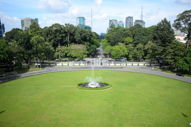 Aerial view of the circular fountain and lawn fronting Reunification Palace toward the city skyline