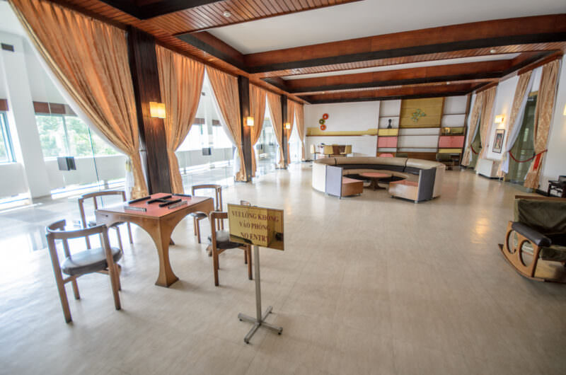 Wooden game table and circular sectional sofa beneath exposed beams in Reunification Palace's games room