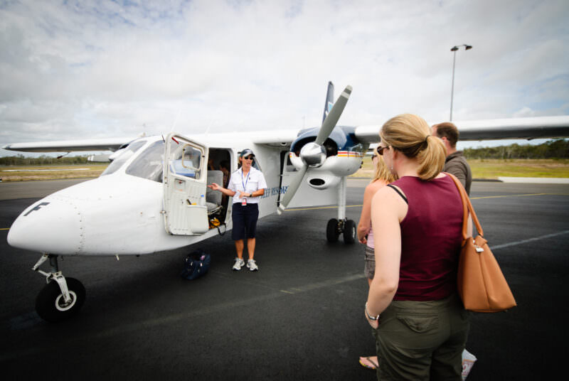 Pilot delivering pre-flight briefing beside Britten-Norman Islander aircraft at Hervey Bay bound for Lady Elliot Island