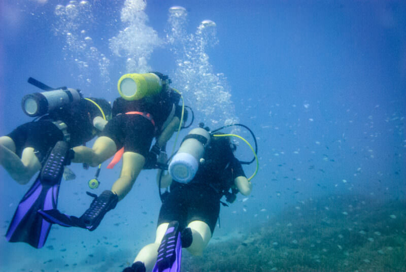 Scuba divers swimming through clear water column off Lady Elliot Island, Great Barrier Reef